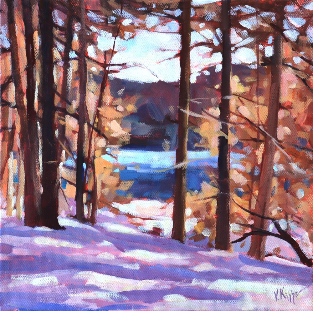 Winter landscape with snow-covered ground and bare trees, featuring a lake in the background.